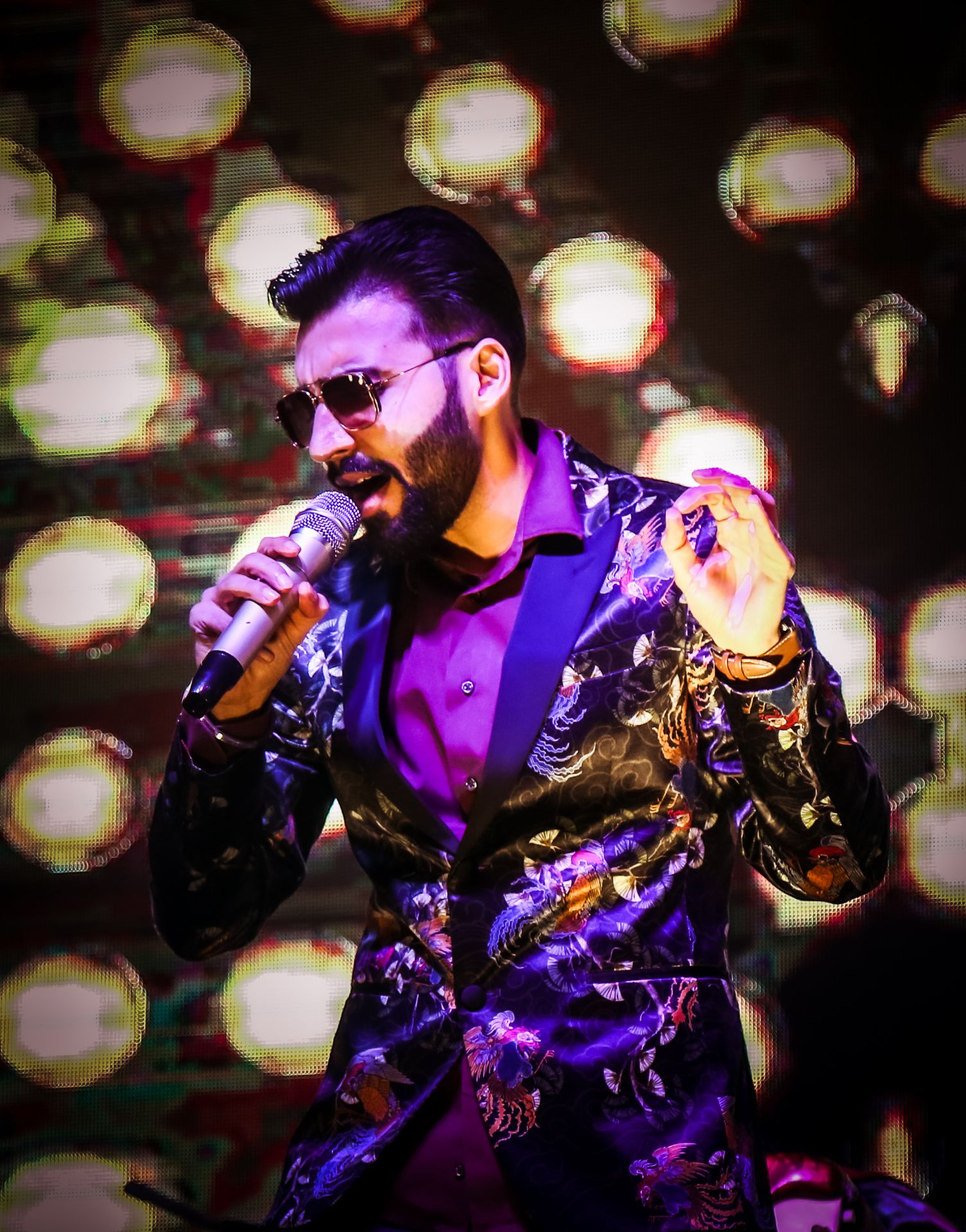 Revaansh Kohli singing under warm stage lights in a sequined jacket