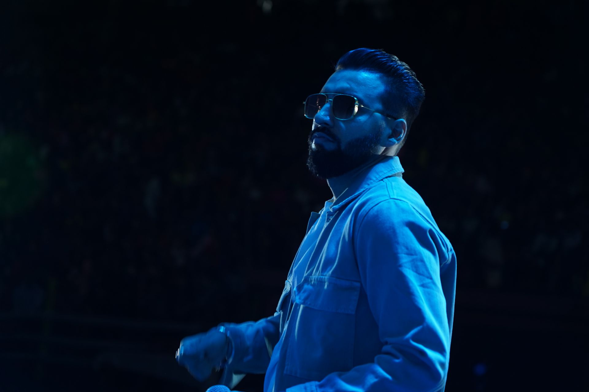 Revaansh Kohli on a dark stage lit in blue light