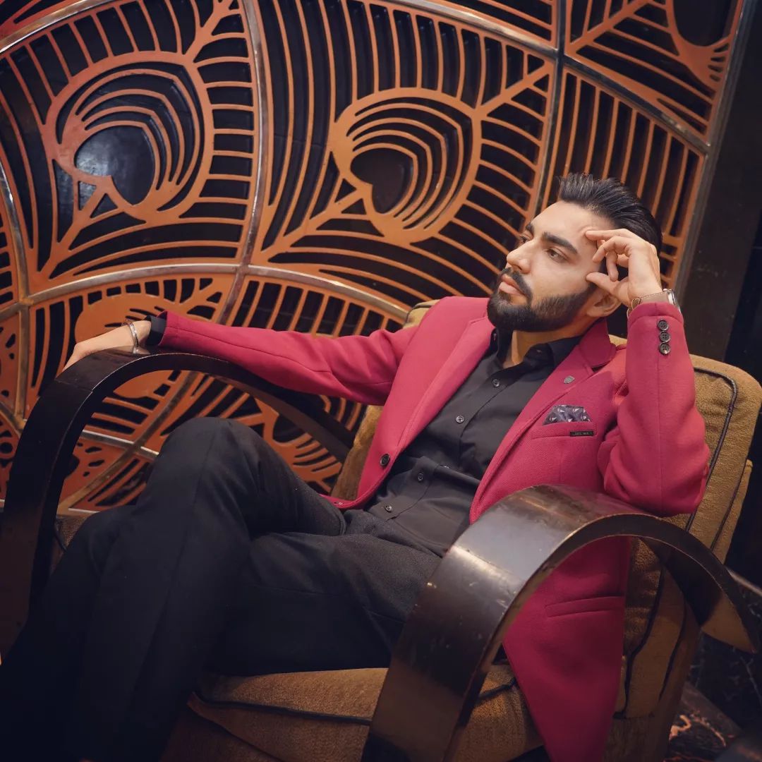Revaansh Kohli relaxing in an ornate chair wearing a red blazer