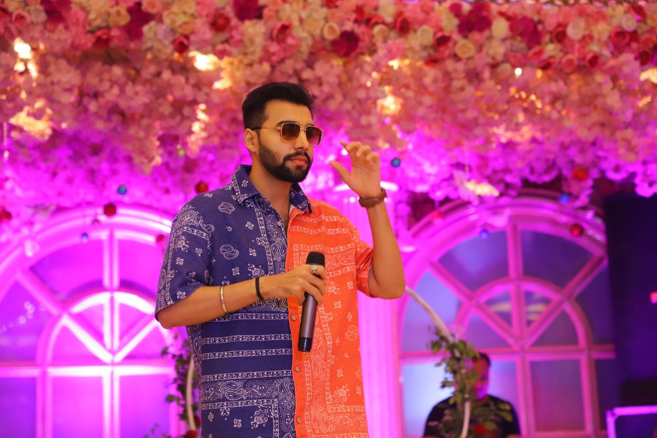 Revaansh Kohli gesturing to guests while singing on a floral stage
