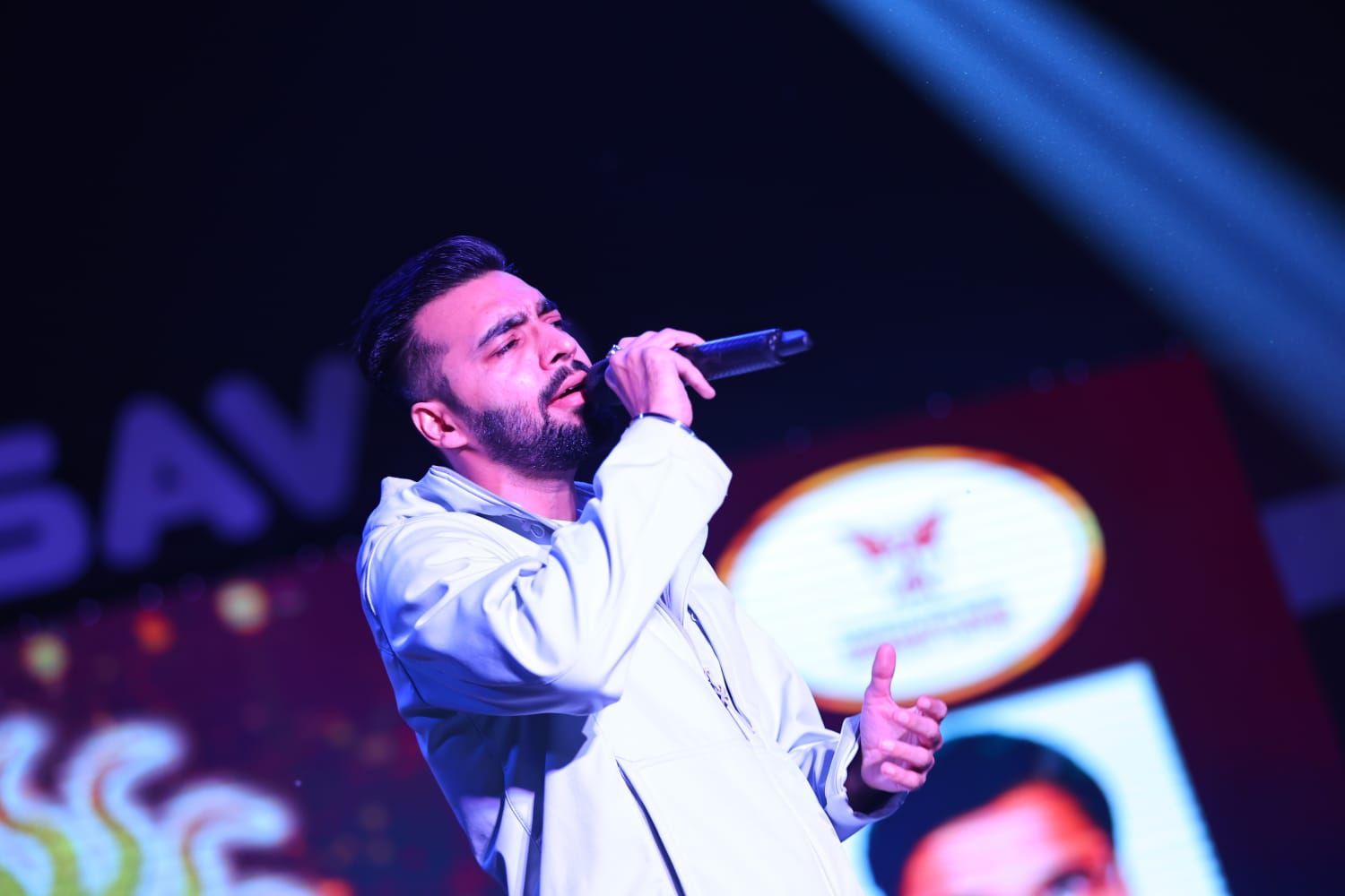 Revaansh Kohli singing live in a white jacket under blue lights
